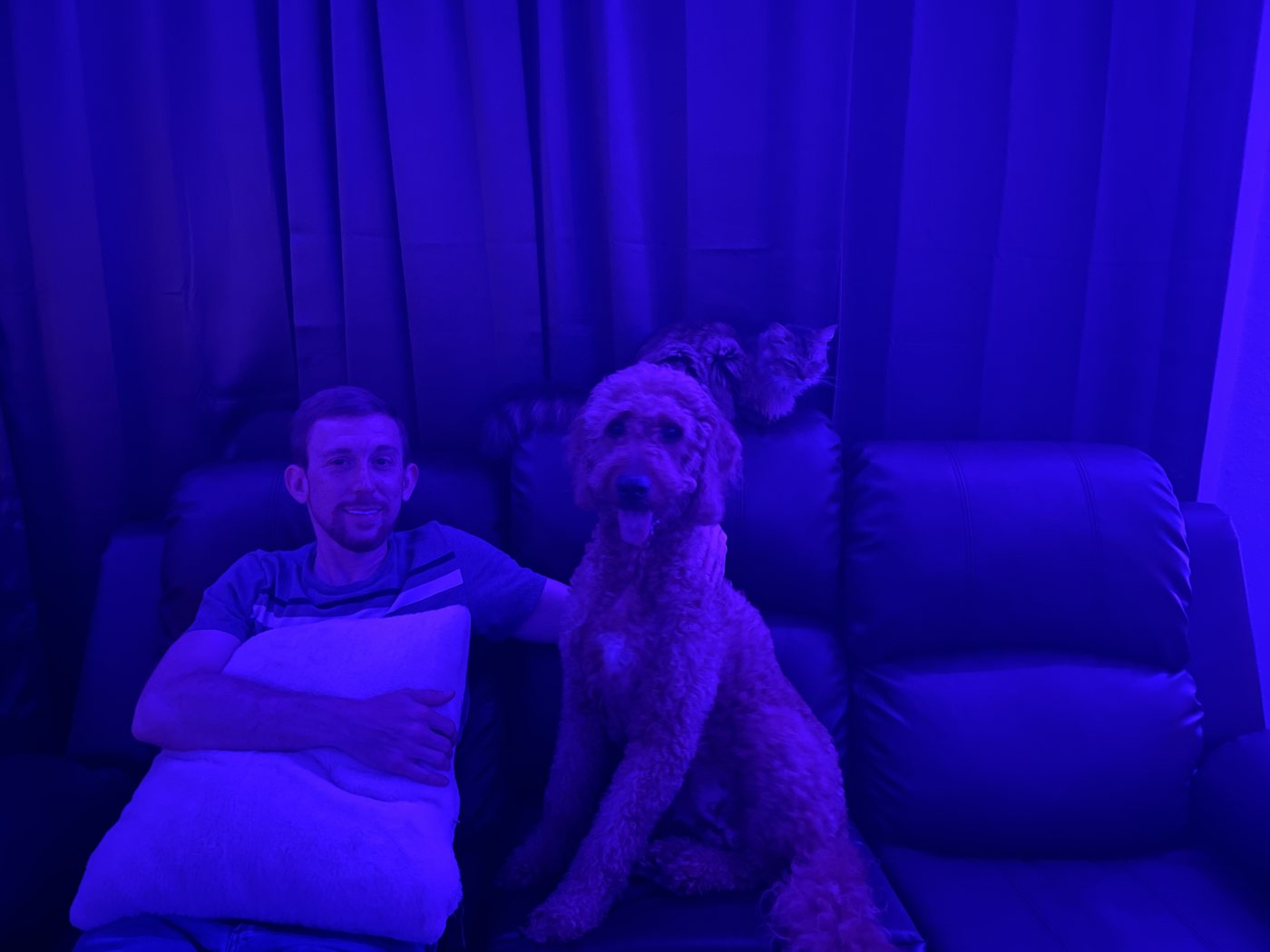 Jordan Polasek sitting on the couch with Autumn beside him under soft blue light, the family cat nestled behind them